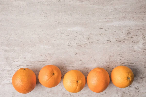 Draufsicht auf Orangenreihe auf Marmoroberfläche — Stockfoto