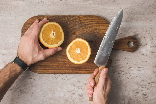 Cropped image of man cutting orange — Stock Photo