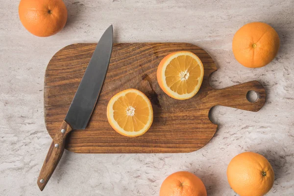 Draufsicht auf geschnittene Orange und Messer auf Holzbrett — Stockfoto