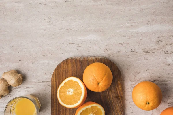 Vue de dessus des oranges sur planche à découper sur plateau en marbre — Photo de stock