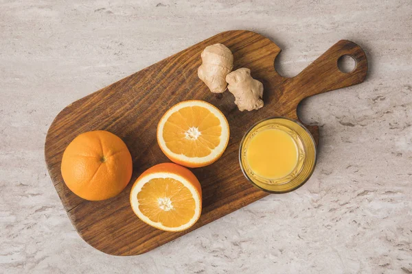 Vue de dessus des oranges, du gingembre et du jus sur planche à découper — Photo de stock