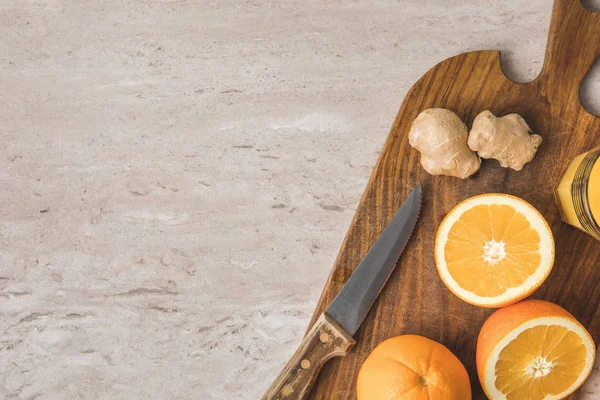 Top view of oranges, knife and ginger on marble surface — Stock Photo