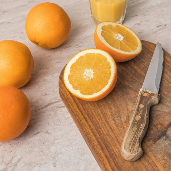 Vue grand angle des oranges et couteau avec planche à découper sur table — Photo de stock