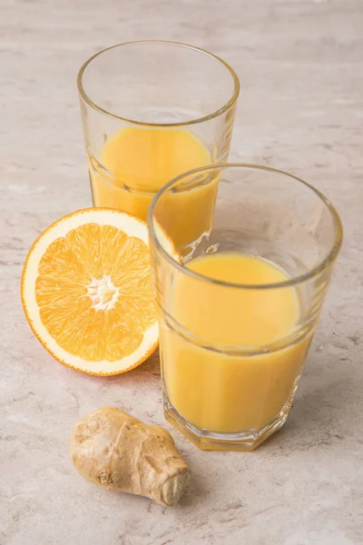 Vista ad alto angolo di succo d'arancia fatto in casa e zenzero sul tavolo di marmo — Foto stock