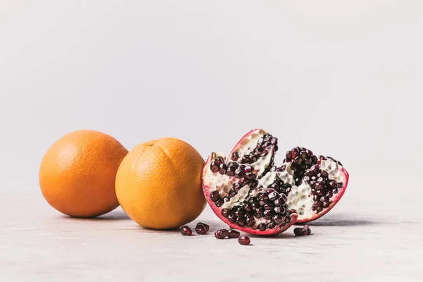 Reife köstliche Orangen und Granatapfel auf Marmoroberfläche — Stockfoto