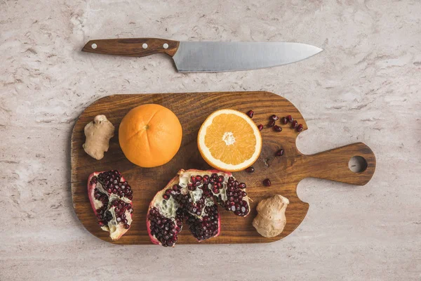 Top view of oranges, pomegranate and ginger on cutting board — Stock Photo