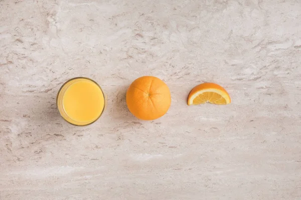 Top view of glass of fresh orange juice and oranges on table — Stock Photo