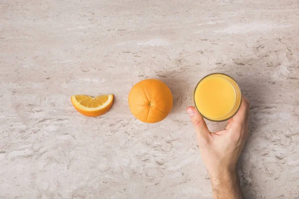 Cropped image of man taking glass of fresh orange juice from table — Stock Photo