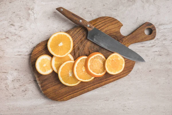 Top view of cut oranges and knife on wooden board — Stock Photo