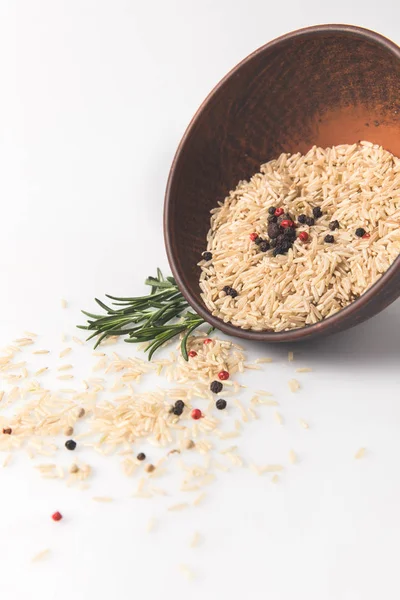 Nahaufnahme von rohem Reis und Gewürzen verschüttet Schüssel auf weißer Oberfläche — Stockfoto