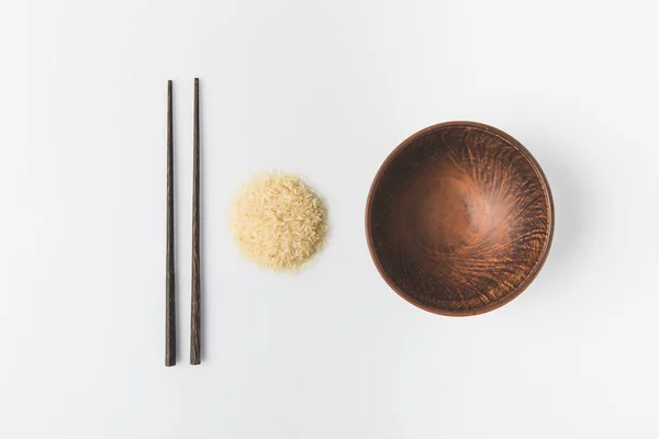 Vista dall'alto del mucchio di riso crudo con ciotola e bacchette isolate su bianco — Foto stock