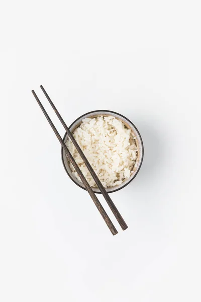 Vue du dessus du bol de riz fraîchement cuit avec des baguettes isolées sur blanc — Photo de stock