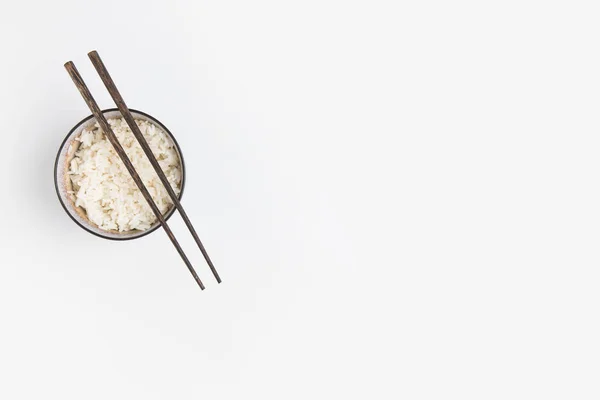 Vue du dessus du bol de riz avec baguettes isolées sur blanc — Photo de stock