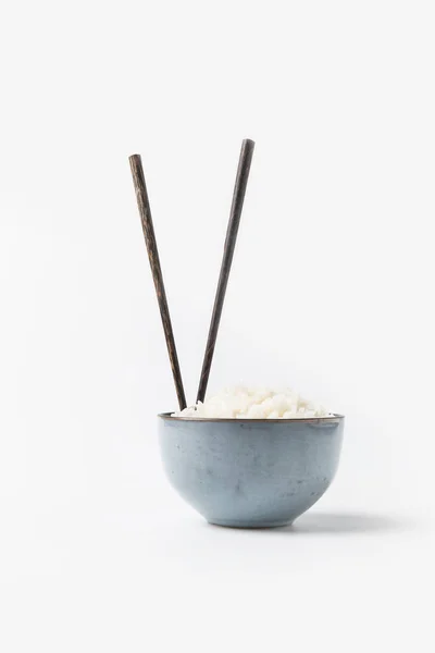 Миска свежеприготовленного риса с палочками на белой поверхности — стоковое фото