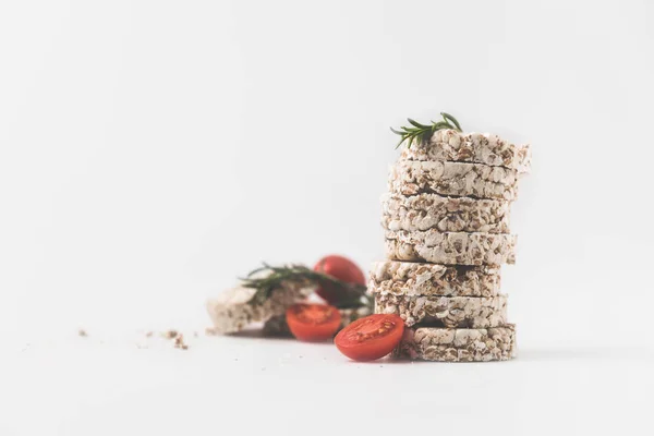 Pila de pasteles de arroz con romero y tomates en la superficie blanca - foto de stock