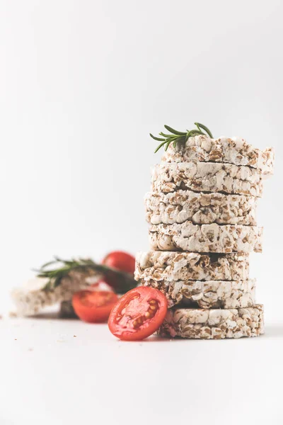 Pilha de bolos de arroz com alecrim e tomate em mesa branca — Fotografia de Stock