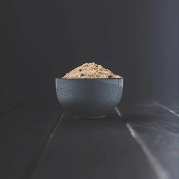 Bowl of raw rice with spices on black table — Stock Photo