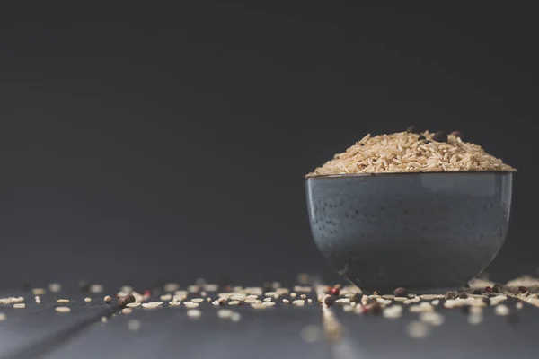 Bowl of raw rice on black table with copy space — Stock Photo