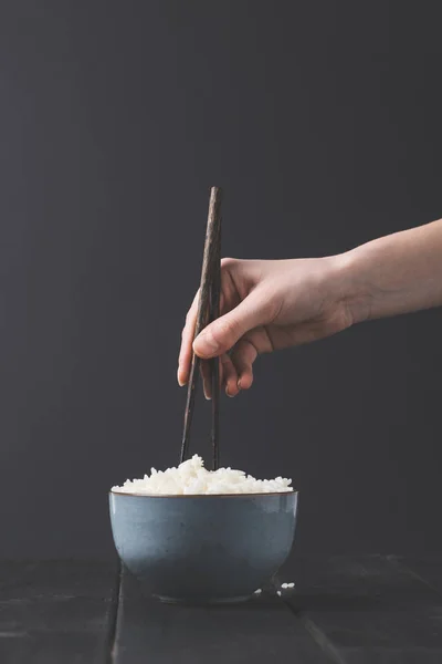 Tiro recortado de la mujer que toma el arroz del tazón con palillos - foto de stock