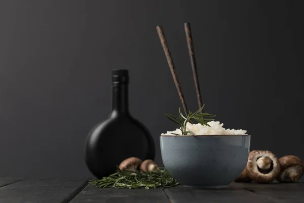 Schüssel Reis mit Pilzen und Flasche Sojasauce auf schwarzer Tischplatte — Stockfoto