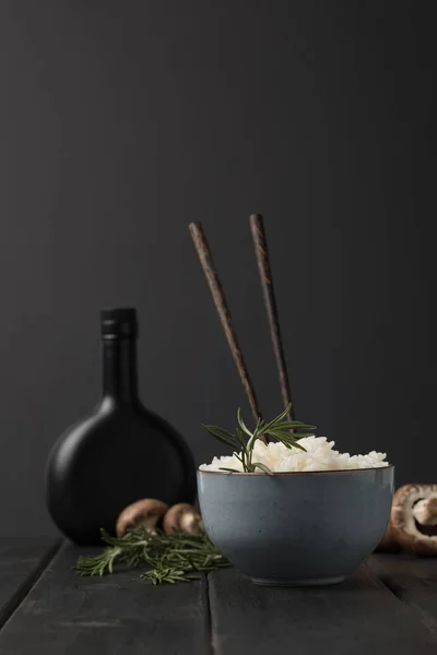 Tazón de arroz sabroso con champiñones y botella de salsa de soja mesa negro - foto de stock