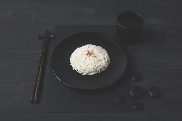 Riso con tazza di tè e bacchette sul tavolo nero — Foto stock