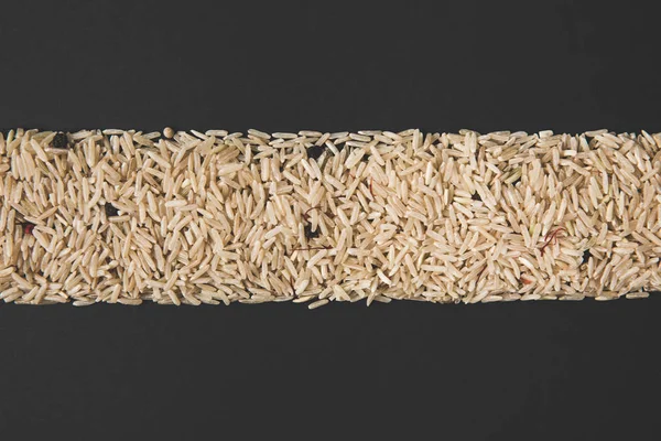 Draufsicht auf Streifen von rohem Reis isoliert auf schwarz — Stockfoto