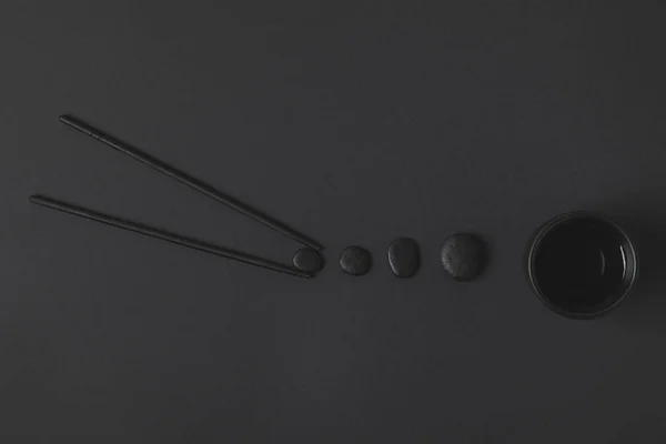 Composición plana creativa de palillo con taza de té chino y guijarros en negro - foto de stock