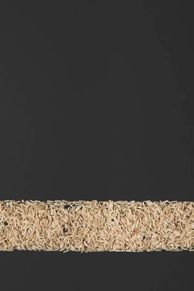 Stripe of raw rice isolated on black with copy space — Stock Photo