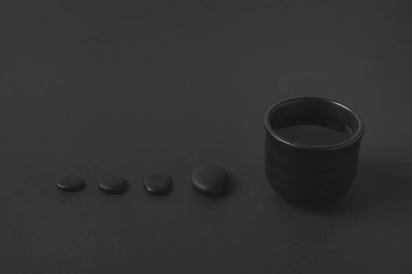 Chinesische Teetasse und Kieselsteine auf schwarzer Oberfläche — Stockfoto