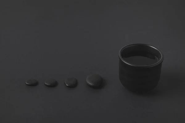 Chinese tea cup and pebbles on black surface — Stock Photo