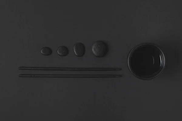 Top view of chopstick with chinese tea cup and pebbles on black — Stock Photo