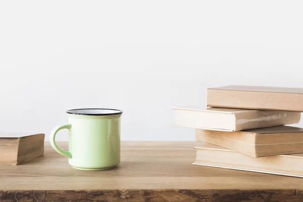 Tazza verde e libri su tavolo di legno su bianco — Foto stock