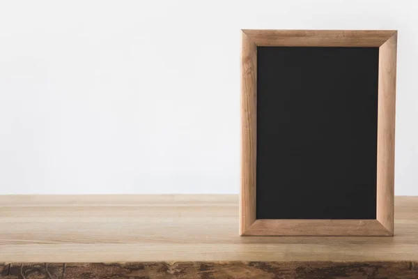 Un tableau noir vide sur table en bois sur blanc — Photo de stock