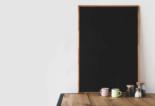 Tasses et café avec grand tableau noir vide sur table en bois sur blanc — Photo de stock