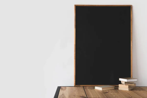 Libri e grande lavagna su tavolo di legno su bianco — Foto stock