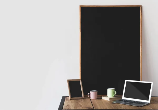 Tableaux noirs vides dans des cadres avec des tasses et un ordinateur portable sur blanc — Photo de stock