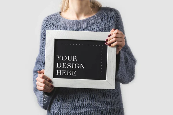 Cropped image of woman holding black board with words your design here isolated on white — Stock Photo