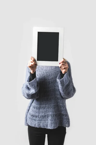 Frau bedeckt Gesicht mit leerer schwarzer Tafel isoliert auf weißem Grund — Stockfoto