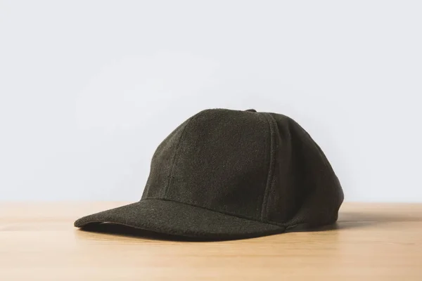 Une casquette noire sur table en bois sur fond blanc — Photo de stock