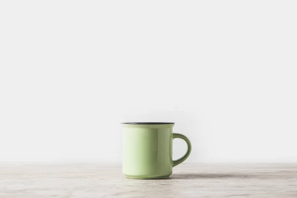 Una taza verde sobre mesa de mármol sobre blanco - foto de stock