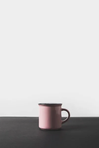 Une tasse rose sur table noire sur blanc — Photo de stock