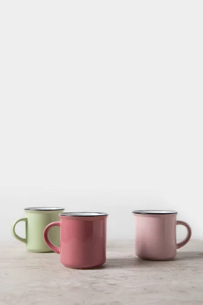 Three colored cups on marble table on white — Stock Photo