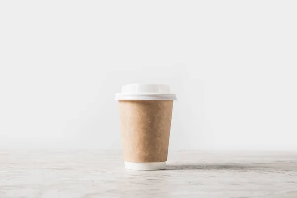 Une tasse à café jetable sur table en marbre sur blanc — Photo de stock