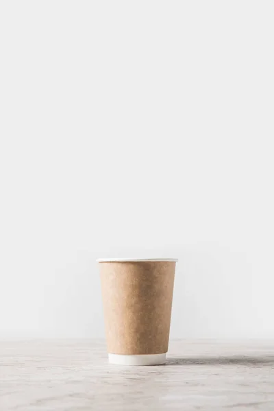 Tasse à café jetable sur table en marbre sur blanc — Photo de stock