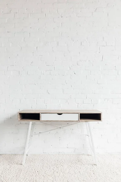 Empty work table in front of white brick wall, mockup concept — Stock Photo