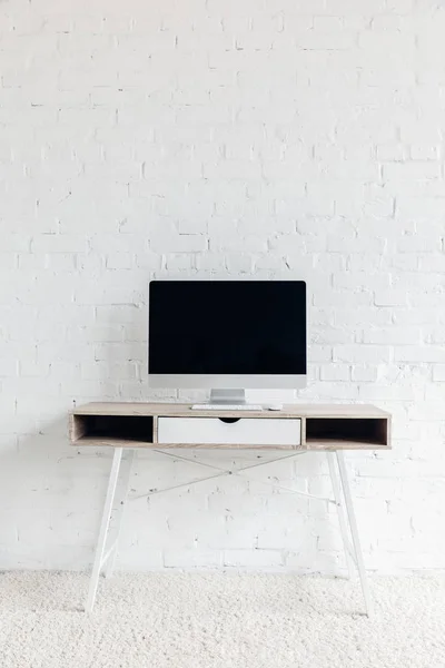 Leerer Copmuter-Bildschirm an leerem Arbeitsplatz vor weißer Backsteinwand, Konzept-Attrappe — Stockfoto
