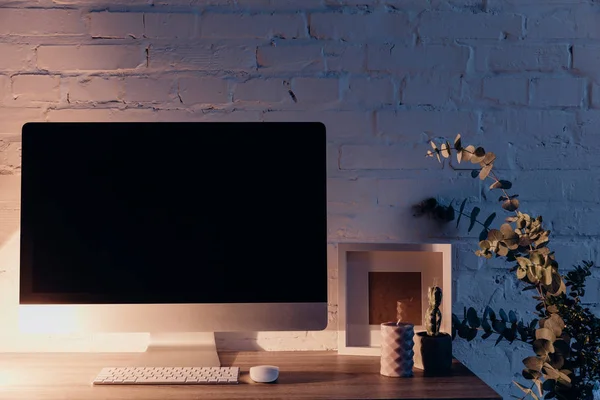 Порожній екран комп'ютера на робочому місці, освітлений настільною лампою ввечері, концепція макету — стокове фото