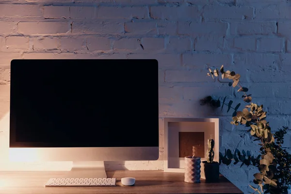 Pantalla copmuter en blanco en el lugar de trabajo iluminado por la lámpara de mesa en la noche, concepto de maqueta - foto de stock