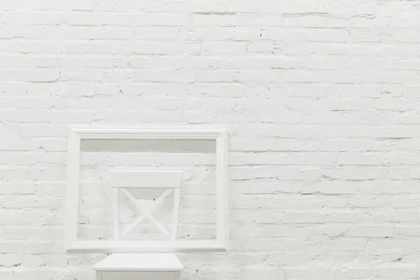 White brick wall with empty frame on chair, mockup concept — Stock Photo